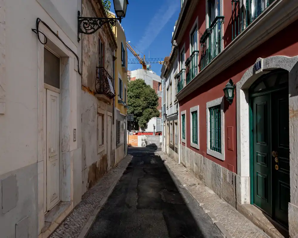 Ruelle urbaine étroite et charmante avec façades traditionnelles, trottoirs pavés et ciel bleu — vue extérieure parfaite pour mettre en valeur l'emplacement et le caractère du quartier.