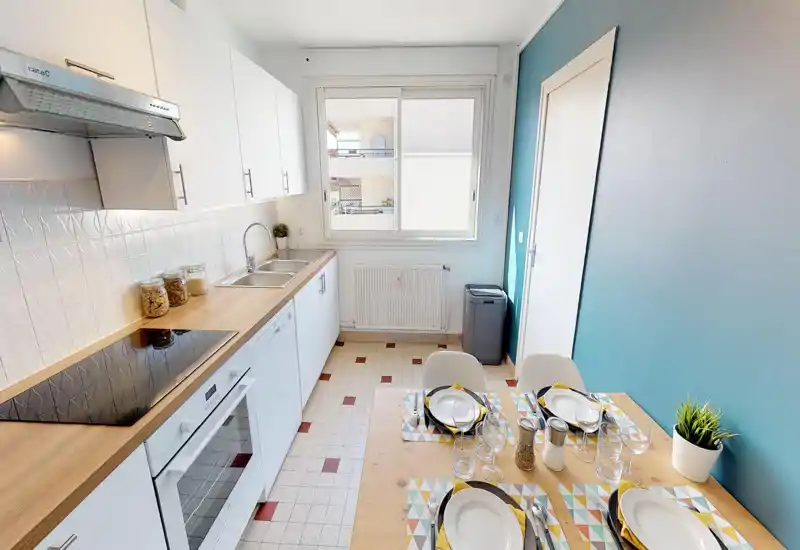 Cucina luminosa e funzionale con piano in legno, piano cottura elettrico e un piccolo angolo pranzo per quattro persone — perfetta per pasti accoglienti e la vita quotidiana.