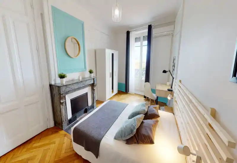 Camera da letto luminosa e di stile con letto matrimoniale confortevole, cuscini decorativi e testiera in legno a doghe; comprende camino in marmo, armadio, scrivania e ampia finestra con luce naturale.