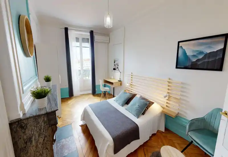 Camera da letto luminosa e di stile con letto matrimoniale, testiera in legno, scrivania vicino alla finestra e pavimento in parquet elegante — perfetta per annunci che evidenziano luce naturale e arredo curato.