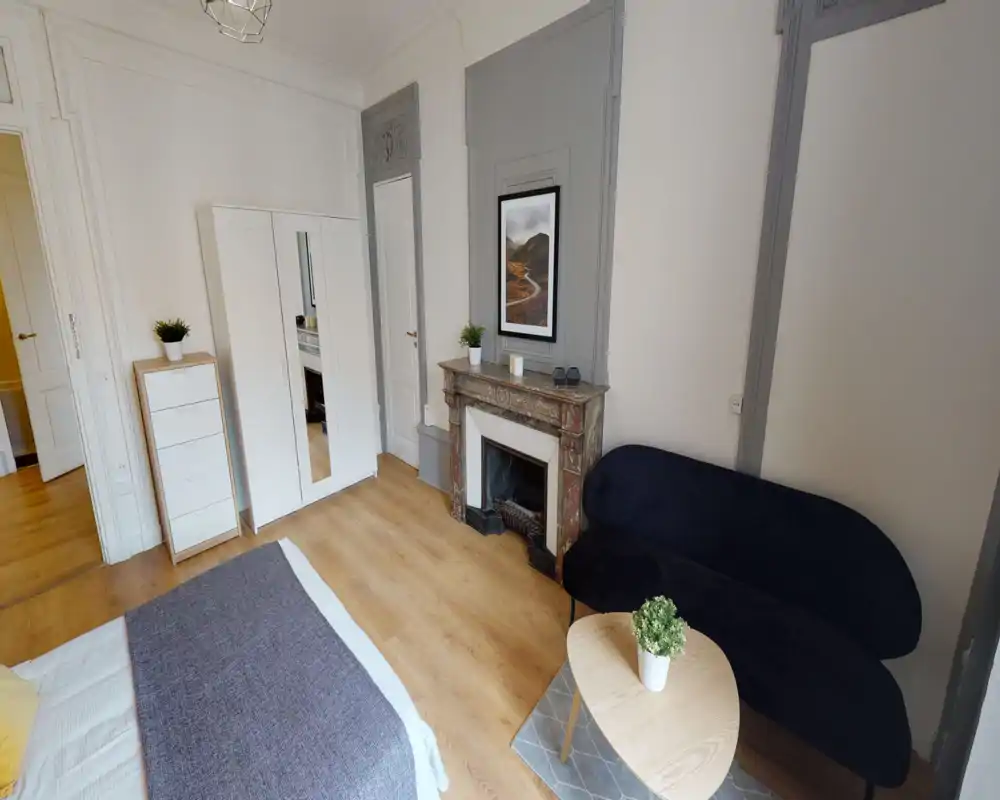 Bright, well-styled bedroom with a large bed, classic fireplace and a comfortable seating area — ideal for a cosy stay.