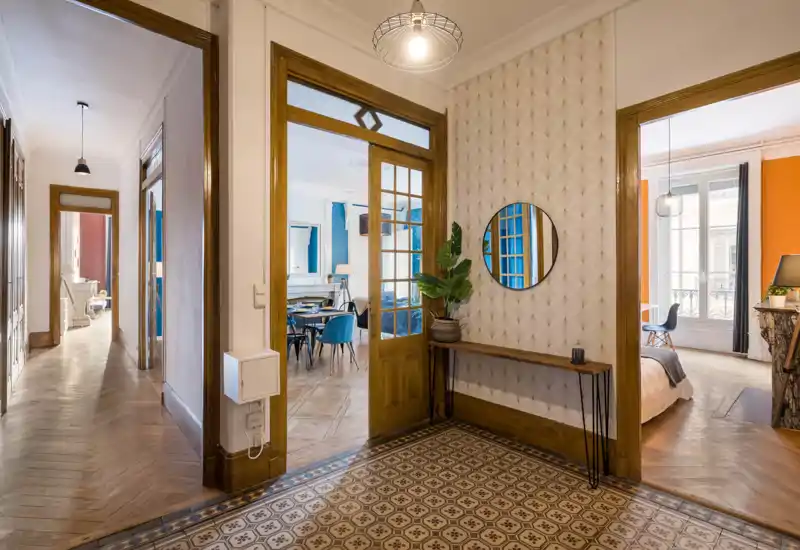 Entrée accueillante avec carreaux de sol décoratifs, miroir mural et console fine ; un espace de transition lumineux et bien décoré menant à la salle à manger et à la chambre.