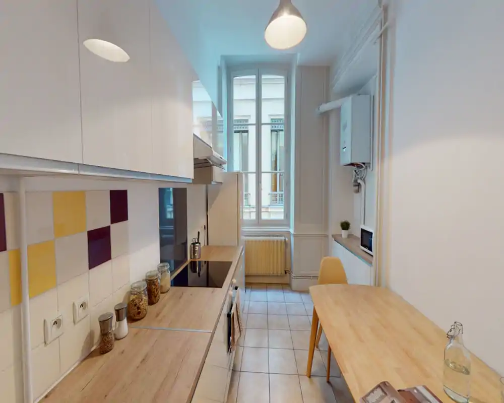 Bright, modern galley kitchen with wood-effect countertops, induction hob, tiled backsplash and a small dining table — neat and functional for everyday cooking.