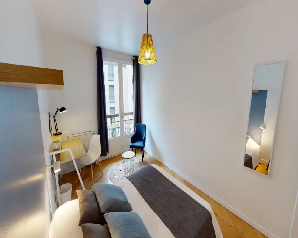 Dormitorio luminoso y bien decorado con cama doble cómoda, textiles suaves y un pequeño espacio de trabajo junto a la ventana. La luz natural y los tonos cálidos crean un ambiente acogedor y moderno, perfecto para alquileres de corta estancia.