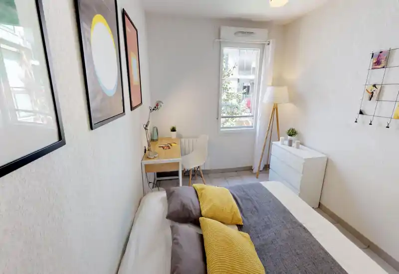 Bright, well-staged bedroom with a double bed, textured throws and a small desk by the window, ideal for rest and work.