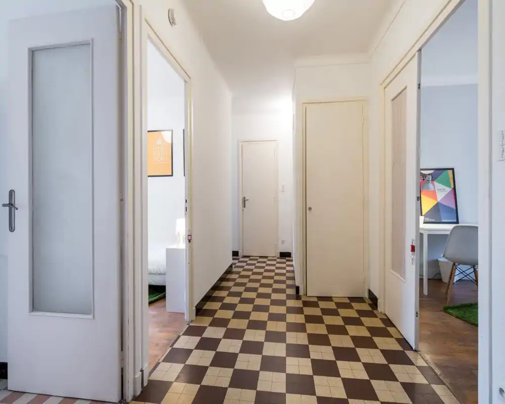 Bright, clean entrance hallway with a checkered tile floor and multiple doors leading to adjacent rooms, ideal for a clear first impression.