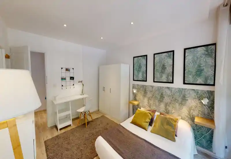 Bright, stylish bedroom with a double bed, patterned headboard and coordinated wall art. Includes bedside shelves, a wardrobe and a small desk — ideal for comfortable stays.