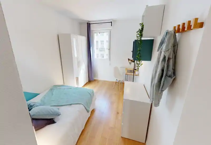 Bright, modern bedroom with a comfortable double bed, wooden floor, wardrobe and a small desk by the window — ideal for a well-lit single or couple.
