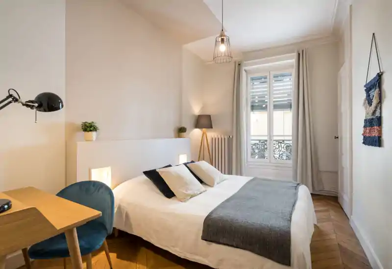 Bright, stylish bedroom with a double bed, cozy textiles and natural light from a large window; ideal for restful stays.