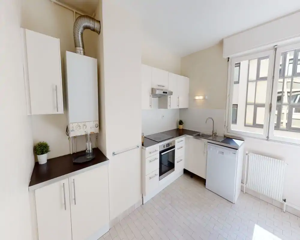 Cucina moderna compatta con ante bianche, forno e lavastoviglie integrati e una grande finestra che garantisce molta luce naturale — layout funzionale.