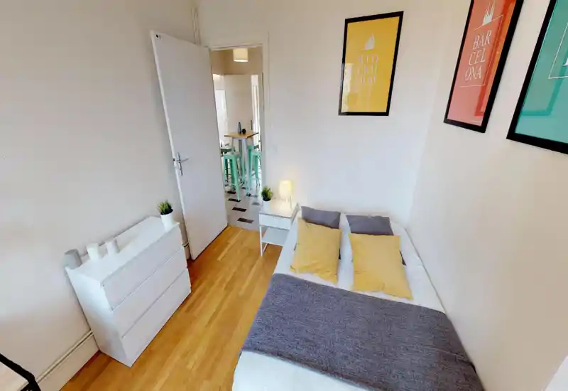 Bright, neatly staged bedroom with a double bed, bedside table and dresser; soft pillows and framed prints create a cozy, modern feel ideal for rental photos.