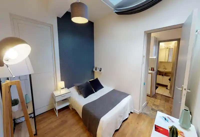 Camera matrimoniale accogliente e luminosa, letto ben rifatto, comodino e illuminazione moderna — perfetta per un soggiorno confortevole.