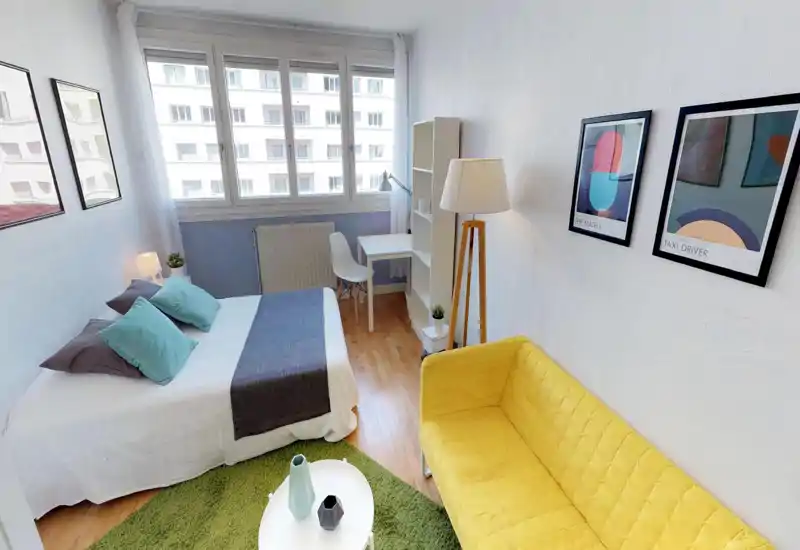 Bright, well-staged bedroom with a full double bed, desk by the window and a cheerful yellow sofa. Natural light from the large window, soft textiles and framed art create a welcoming rental-ready space.
