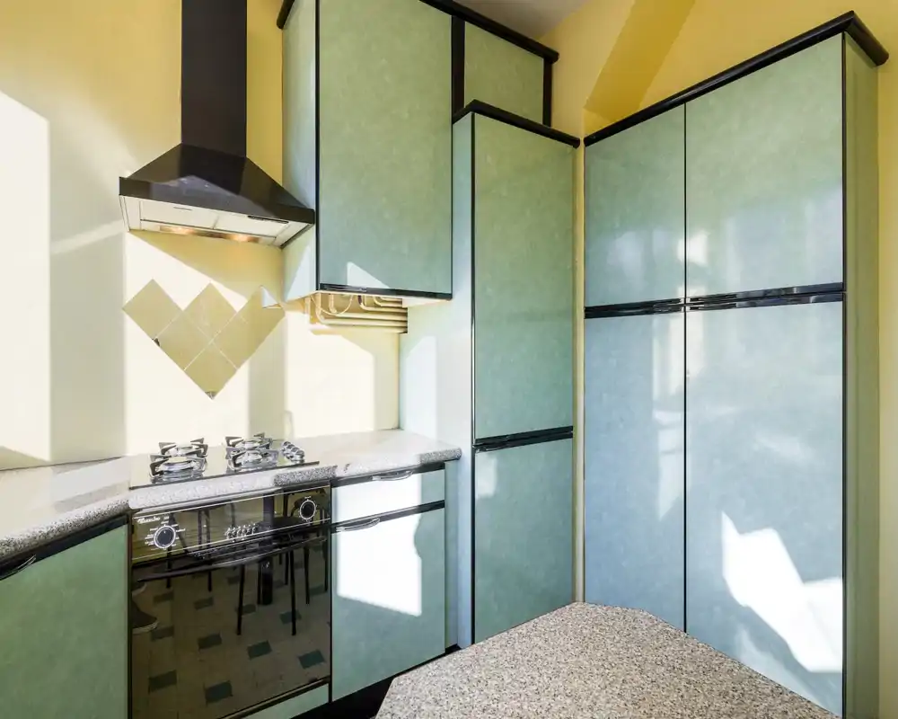 Bright, compact kitchen with mint-green cabinets, a gas hob and built-in oven; plenty of natural light and coordinated countertops.