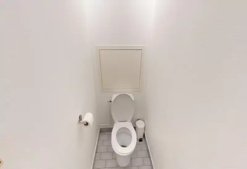 Compact, clean WC with white fixtures, tiled floor and a small waste bin. Well-lit and simply styled, suitable for a rental listing.