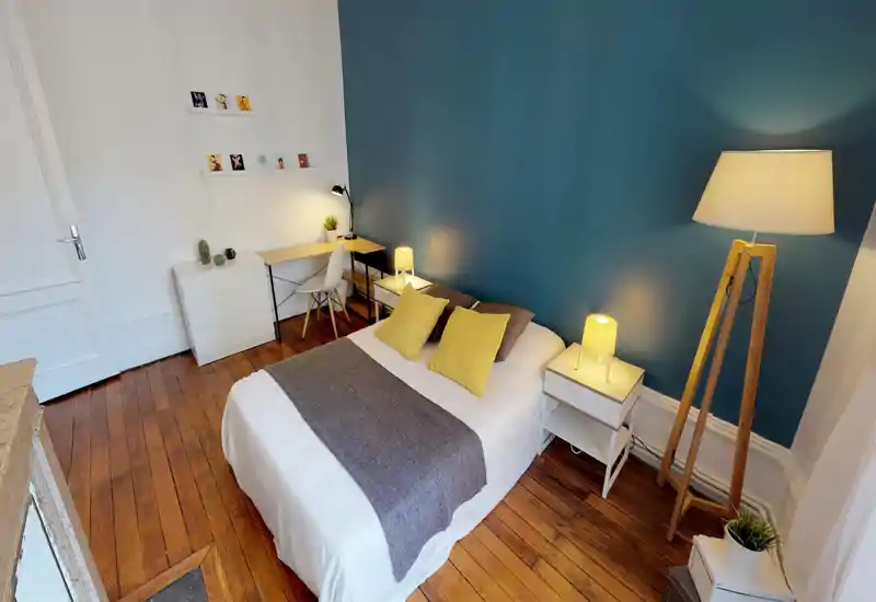 Camera da letto luminosa e curata con letto matrimoniale, lampade da comodino calde e cuscini gialli coordinati su una parete accentuata color teal.