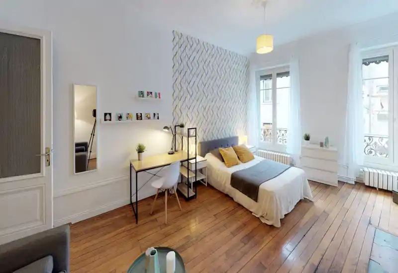 Camera da letto luminosa e di stile con un comodo letto matrimoniale, pavimenti in legno, scrivania e ampie finestre che lasciano entrare molta luce naturale.