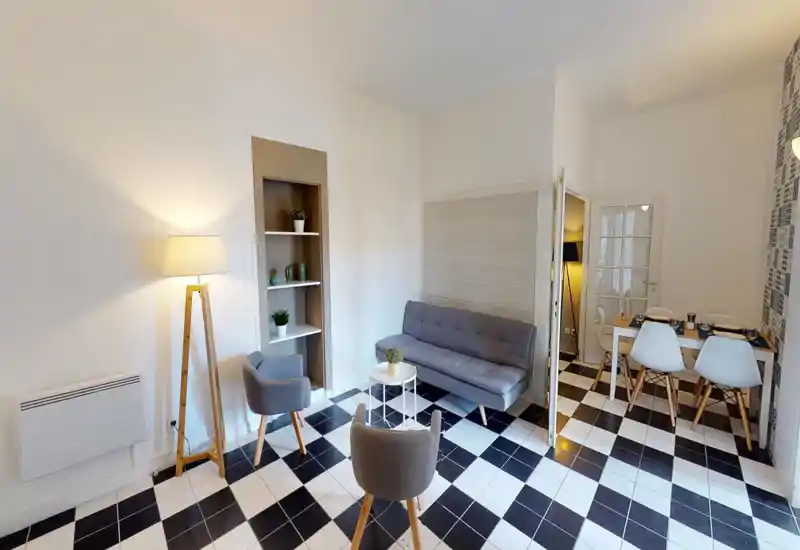 Bright, stylish living room with a gray sofa, two armchairs, decorative shelving and a small coffee table — perfect for relaxing or entertaining.