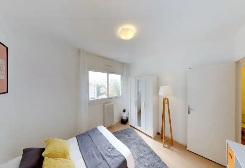 Camera da letto luminosa e minimal con una grande finestra, letto matrimoniale con biancheria neutra e cuscini testurizzati, armadio con specchio e lampada da terra per un’atmosfera calda.