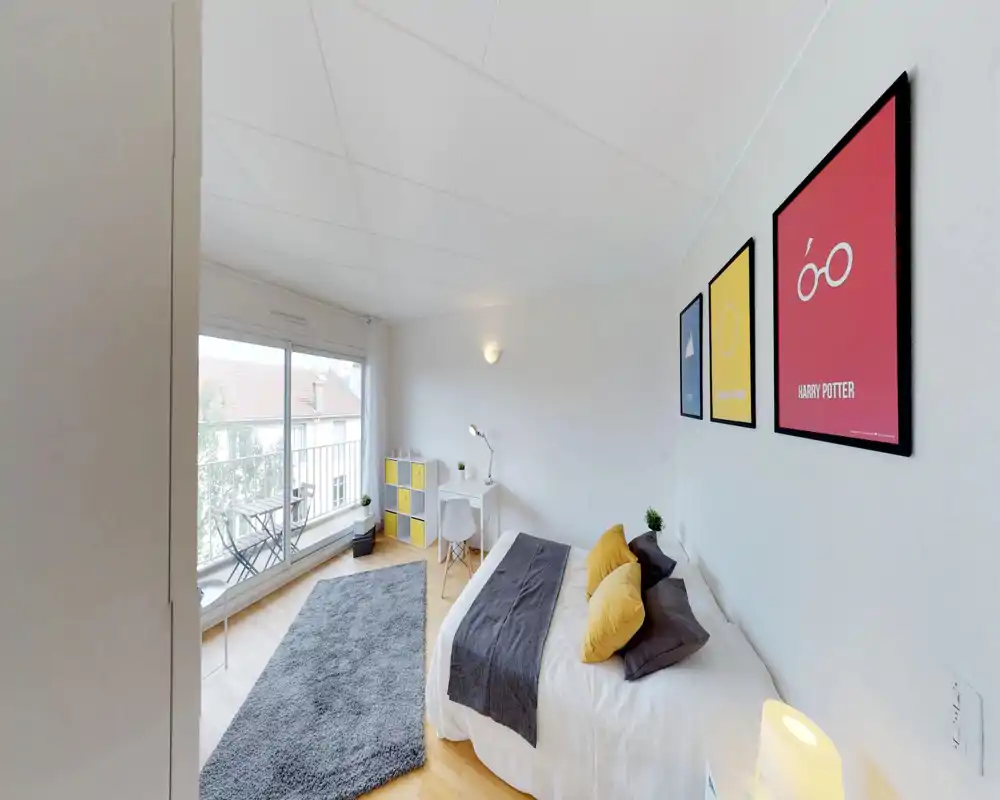 Camera da letto luminosa e moderna con letto matrimoniale comodo, cuscini decorativi e morbido tappeto. Ampia finestra scorrevole si apre su un piccolo balcone con posti a sedere esterni; una scrivania ordinata offre un'area studio.