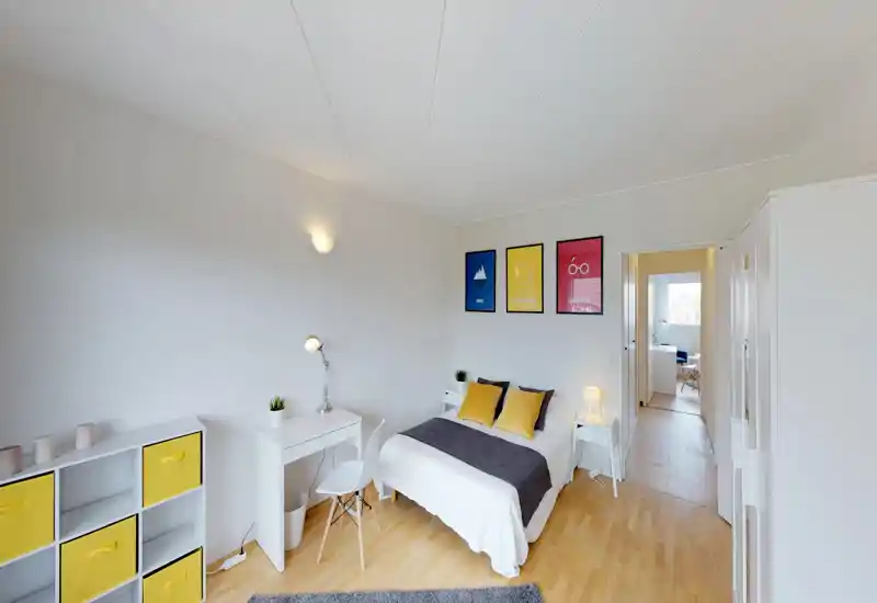 Camera da letto luminosa e ben arredata con letto matrimoniale, comodini e accenti gialli coordinati; perfetta per annunci in affitto che vogliono evidenziare un'area notte moderna e ordinata.