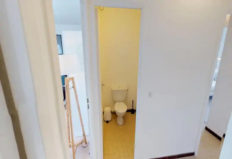 Petite salle de bain avec WC standard, sol carrelé et éléments simples ; éclairage neutre et décoration minimale.