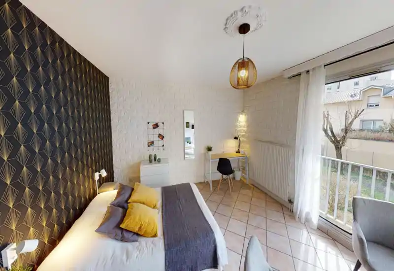Bright, stylish bedroom with patterned accent wall, large double bed dressed with mustard and gray cushions, and a small desk by the window letting in abundant natural light.
