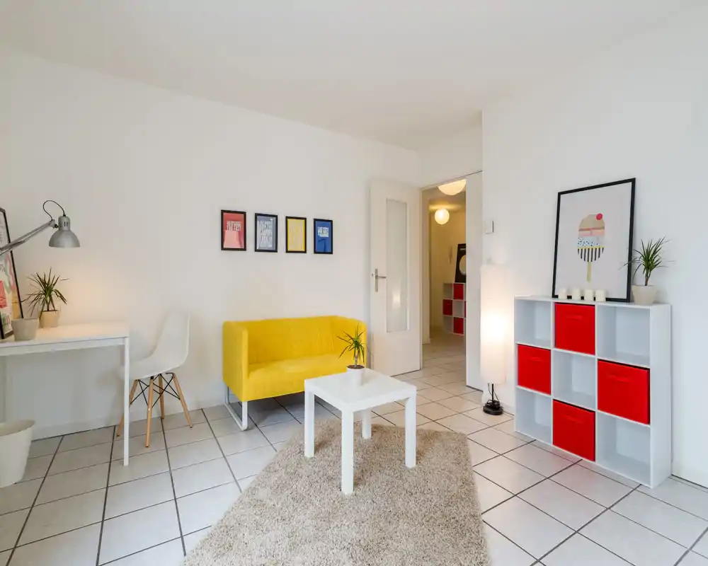 Bright, modern living room with a yellow sofa, white coffee table on a soft rug, and colorful storage cubes — well styled and inviting for guests.