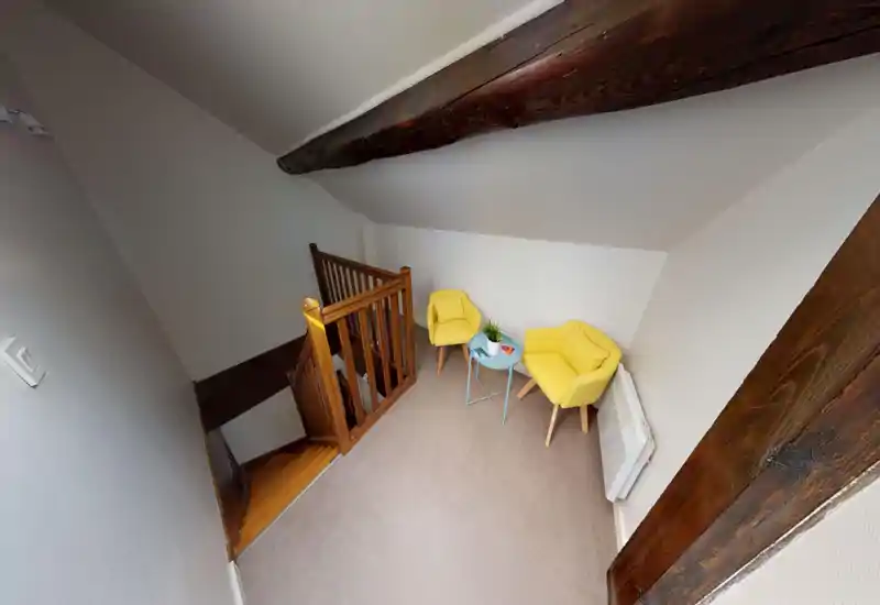Small landing/entrance area at the top of a staircase with two yellow armchairs and a small table — ideal as a cozy reading nook or waiting spot.