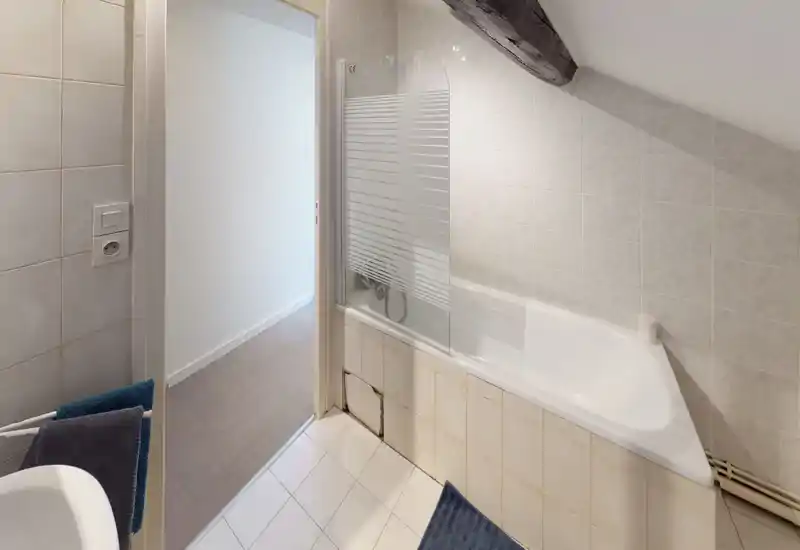 Tidy bathroom with a built-in bathtub, half-glass shower screen and tiled walls. Clean, well-lit space suitable for a rental listing.