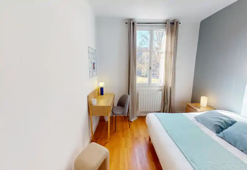 Bright, well-styled bedroom with a double bed, bedside table and a small desk by the window. Soft textiles, natural light and warm wood floor create a comfortable atmosphere ideal for rental listings.