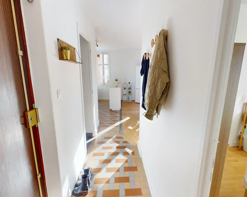 Bright, welcoming entrance hallway with patterned tiled floor, coat hooks and natural light streaming in.
