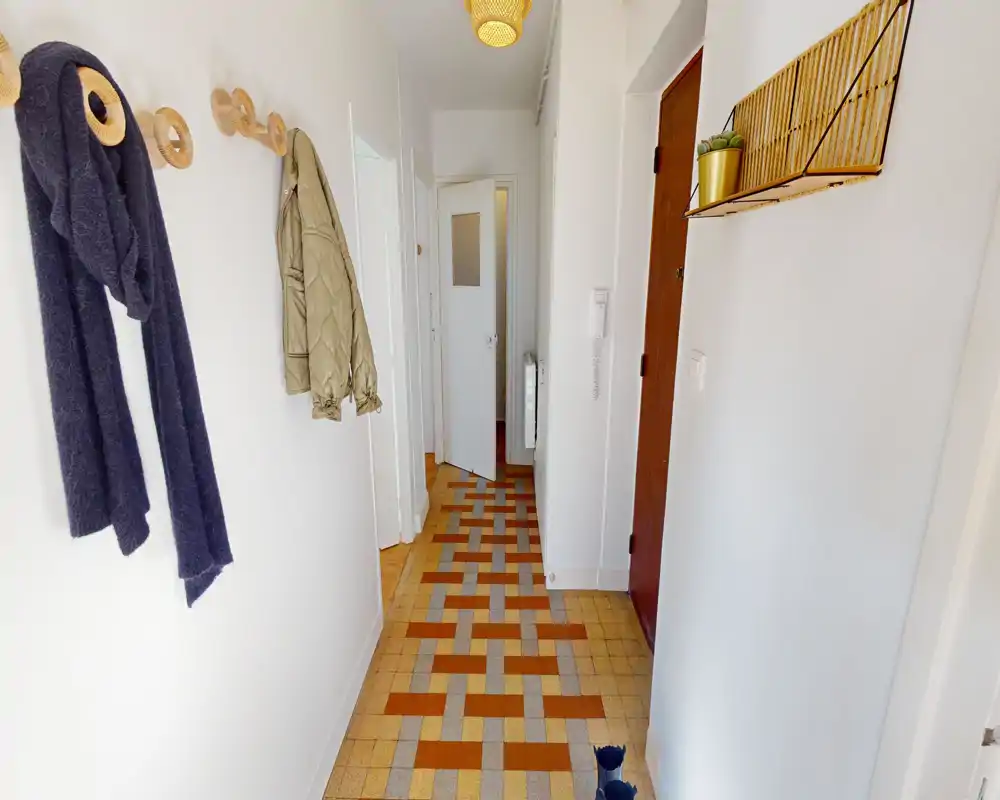 Bright, tidy entrance hallway with decorative wall hooks and patterned tile flooring—good natural light and clean lines.