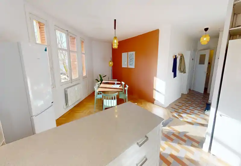 Coin repas lumineux avec une petite table en bois, chaises pastel et mur accent terracotta — idéal pour des repas chaleureux à la lumière naturelle.