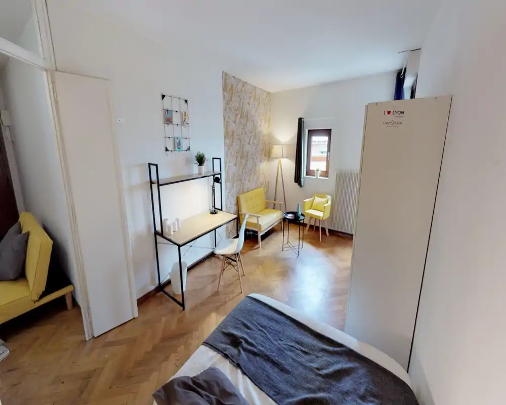 Dormitorio luminoso y con estilo: cama en primer plano, escritorio compacto con estantería y un rincón acogedor con sillones amarillos y lámpara de pie.