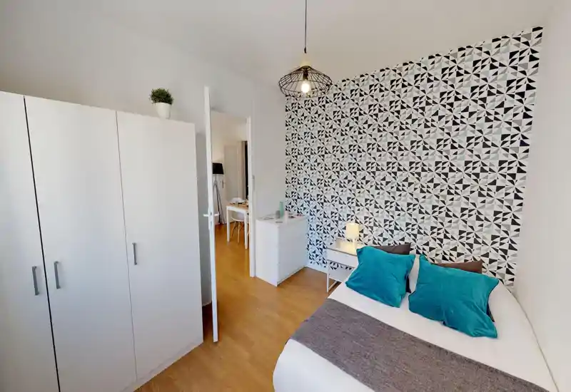 Bright, well-styled bedroom with a patterned feature wall, white furnishings and teal cushions creating a fresh, modern look.
