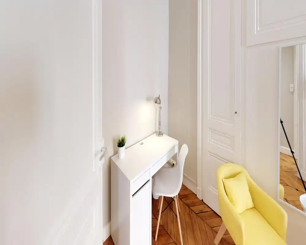 Bright, well-staged living corner with a compact white desk, reading lamp and a cheerful yellow armchair on warm parquet floors — ideal for work or relaxation.