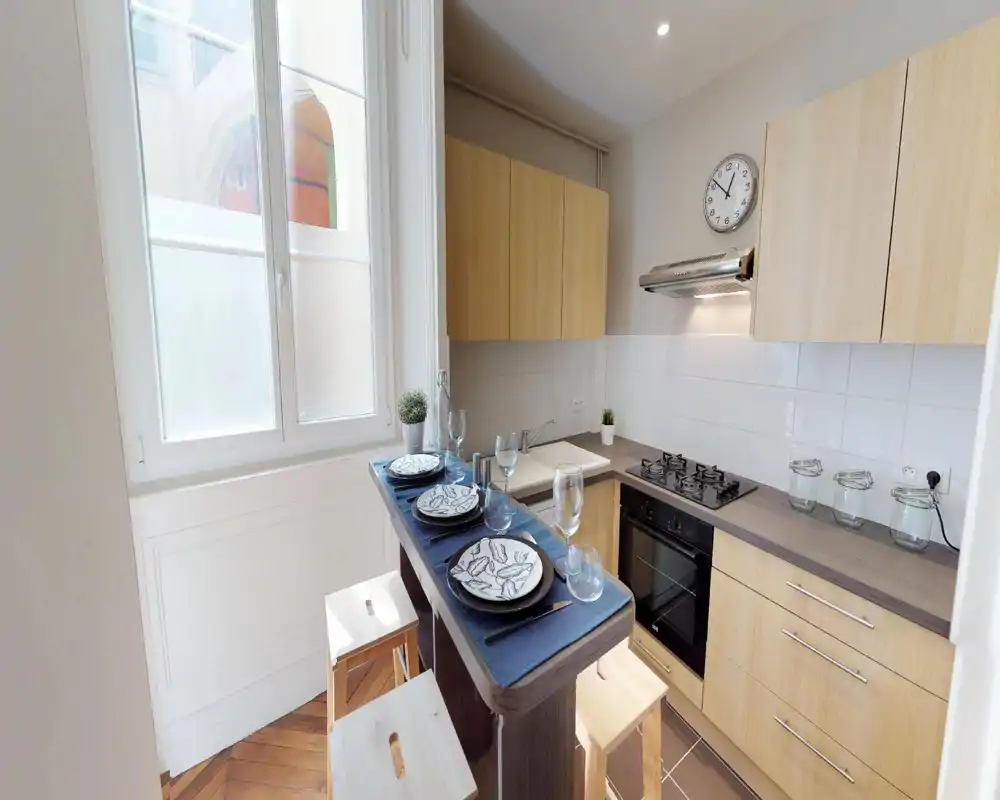 Bright, compact kitchen with light wood cabinets, a gas hob and a built-in oven; a small breakfast bar set for four makes it ideal for city rentals.
