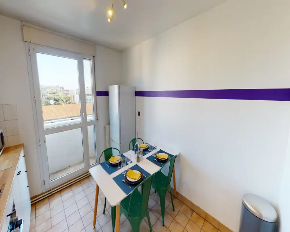 Bright, compact kitchen with a dining table set for four, large window/door to a small balcony and simple modern finishes.
