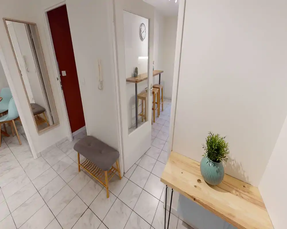 Entrée lumineuse et rangée avec sol carrelé, miroir, banc avec range-chaussures et petite console en bois avec plante décorative — belle première impression.