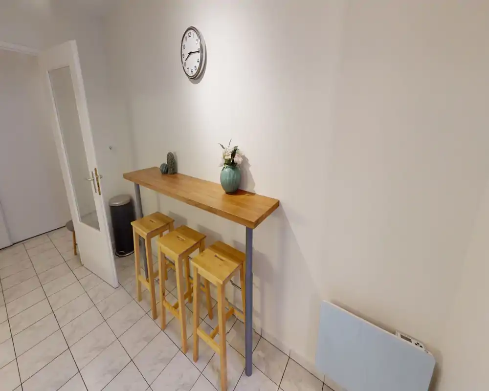 Bar petit-déjeuner lumineux et minimaliste avec trois tabourets en bois, un plateau en bois et une décoration simple — idéal pour repas rapides ou coin repas compact.