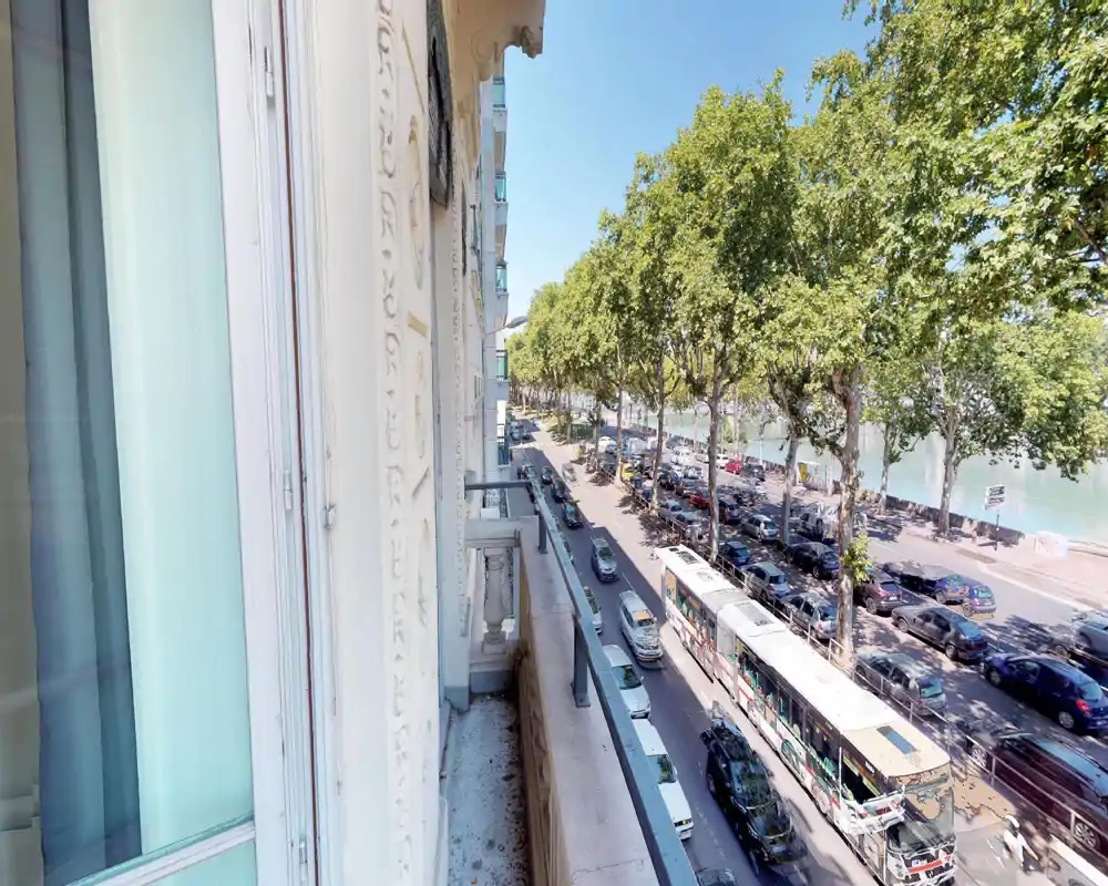 Exterior view showing trees and a street; image is heavily distorted but suggests a balcony or street-facing window view.