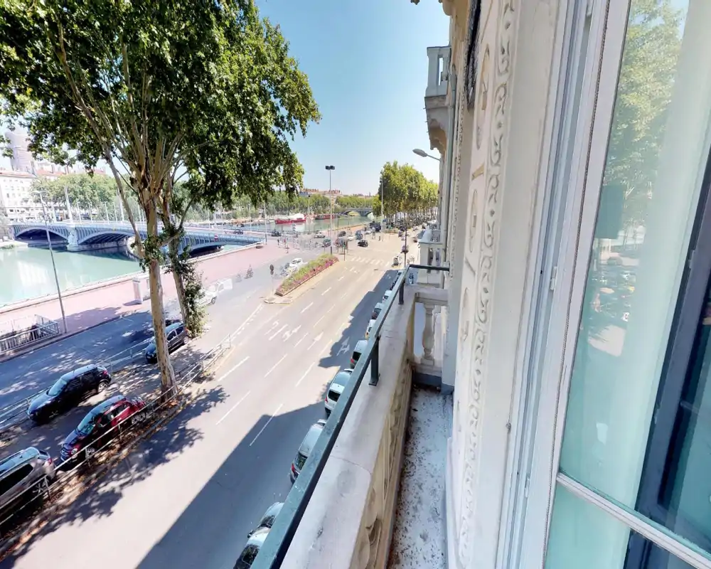 Outdoor street/riverfront view taken from a window or balcony; trees, a bridge and a roadway are visible despite heavy digital distortion.