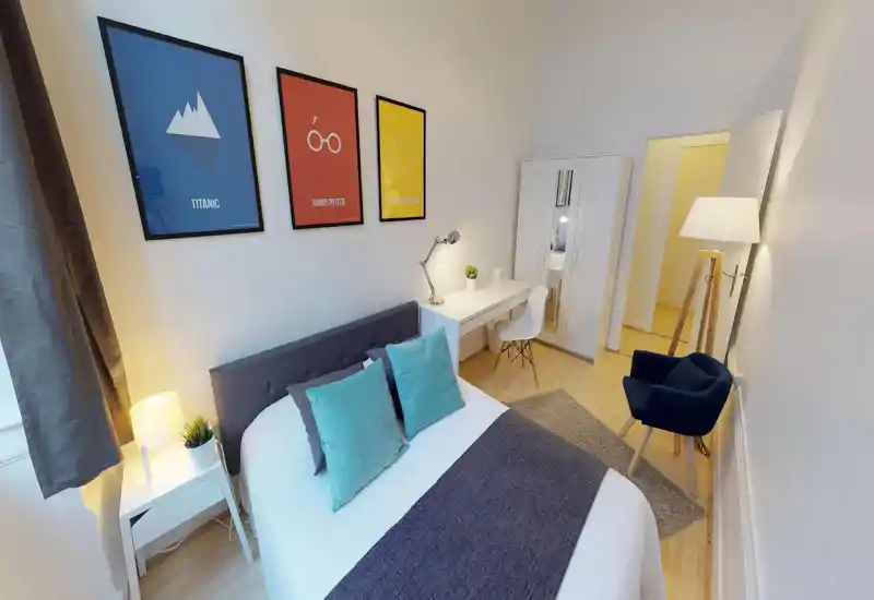 Bright, stylish bedroom with a comfortable double bed, bedside table and desk area — well-lit and tastefully decorated for a cozy stay.