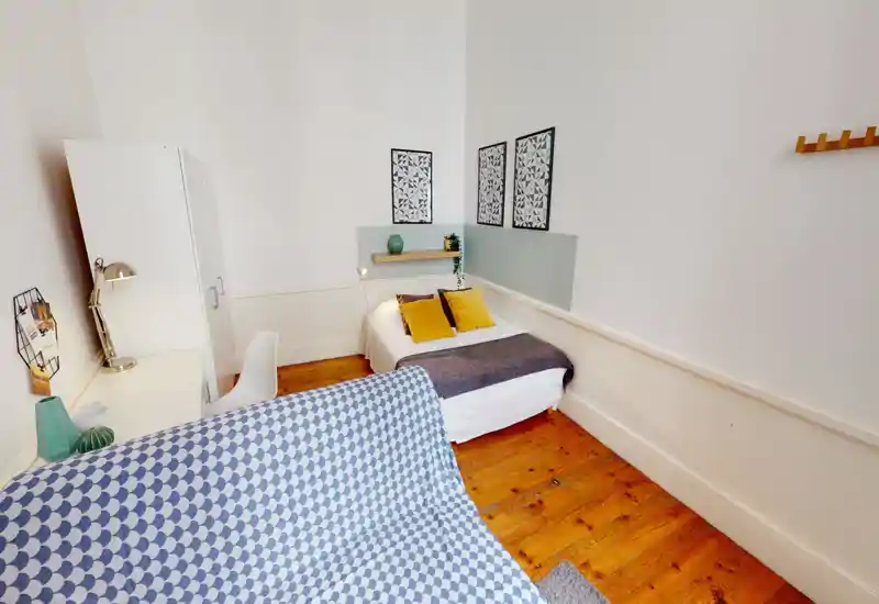 Bright, cozy bedroom with a double bed dressed in white linens, mustard accent cushions and a grey throw, wooden floors and minimalist wall art.