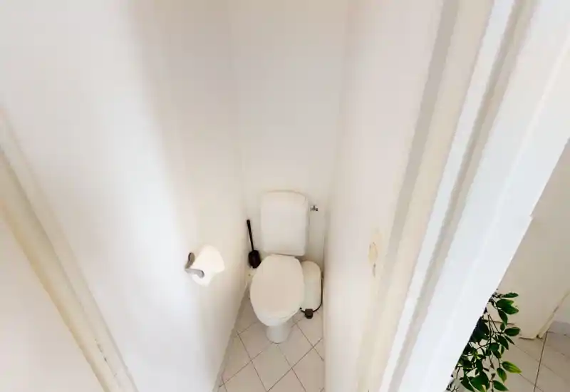Petite salle d'eau équipée d'un WC standard, sol carrelé et murs blancs — espace WC lumineux et propre, idéal pour un petit appartement.