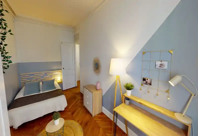 Camera da letto luminosa e curata con letto matrimoniale, tessili morbidi, pavimento in parquet e decorazioni di buon gusto; scrivania compatta e lampade calde per un angolo studio accogliente.