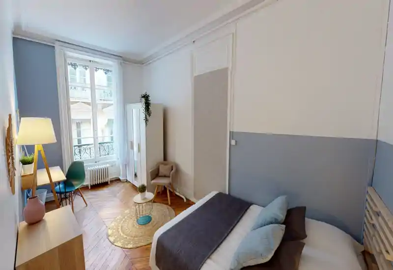 Camera da letto luminosa e di stile con un comodo letto matrimoniale, cuscini morbidi e un tappeto accogliente. La grande finestra illumina la stanza e il parquet in legno aggiunge carattere.