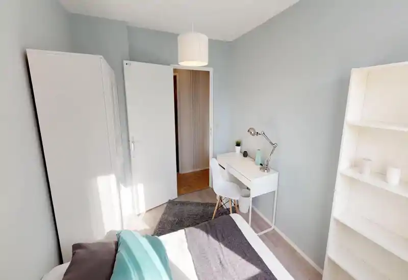 Camera da letto luminosa e ben curata con letto visibile, tessili morbidi e una piccola scrivania: perfetta per una persona o uno studente.