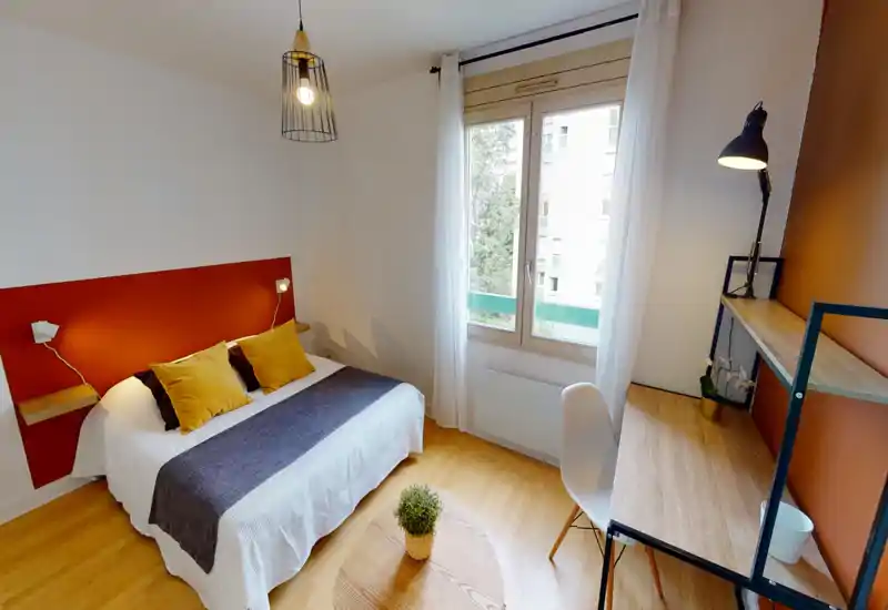 Bright, well-staged bedroom with a double bed, warm accent wall and cozy textiles; a desk by the window offers a practical workcorner.